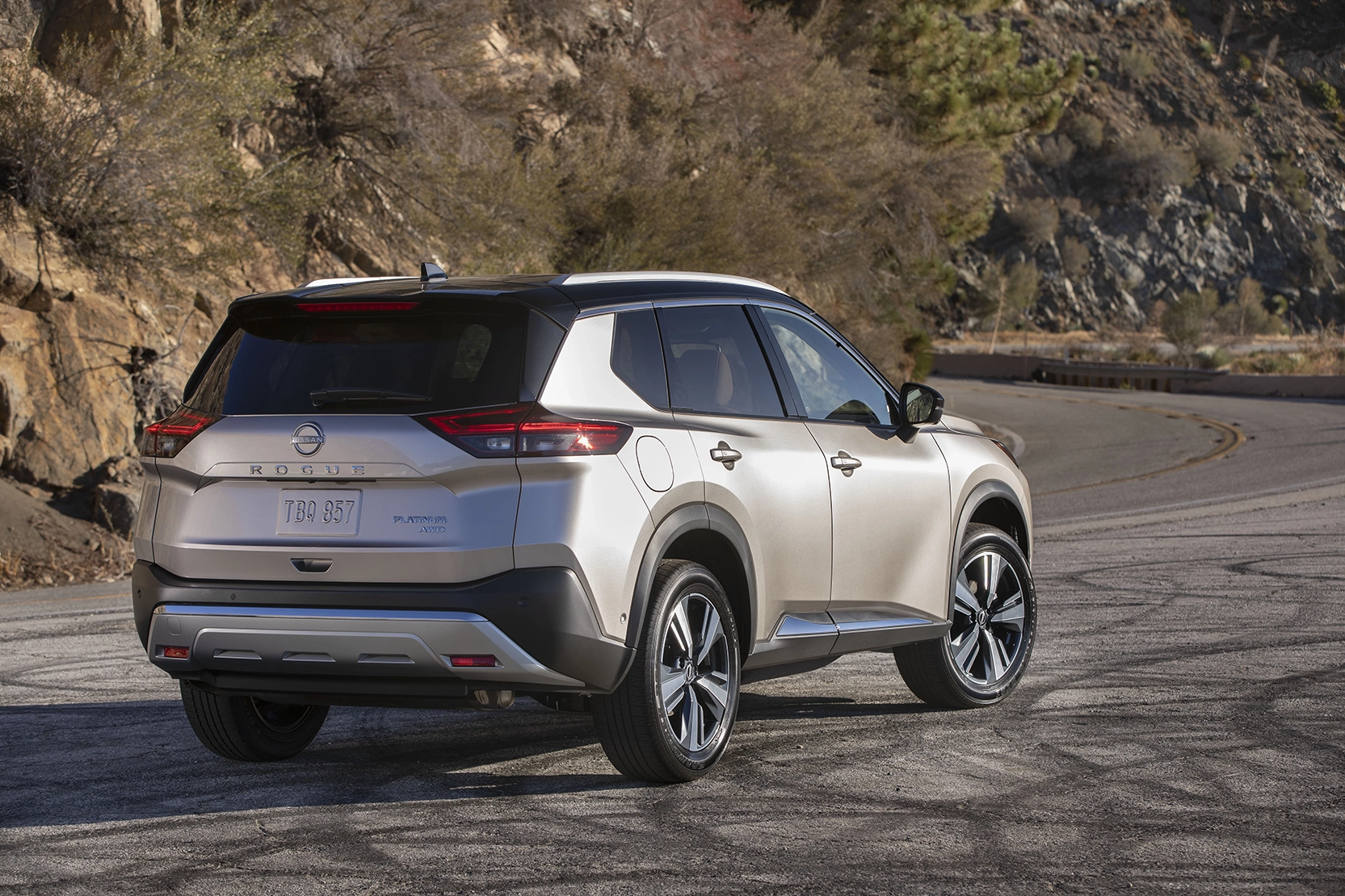 back view of champagne suv 2022 nissan rogue on rocky road in saguenay